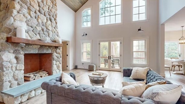 A spacious living room with a stone fireplace, large windows, and a cozy seating area. - NEW BUILD! Mountain views, minutes from Squam's Sandwich Beach and boat ramp!  (Center Sandwich)