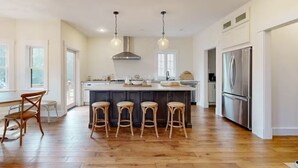 A spacious kitchen with a large island, wooden flooring, and modern appliances. - NEW BUILD! Mountain views, minutes from Squam's Sandwich Beach and boat ramp!  (Center Sandwich)