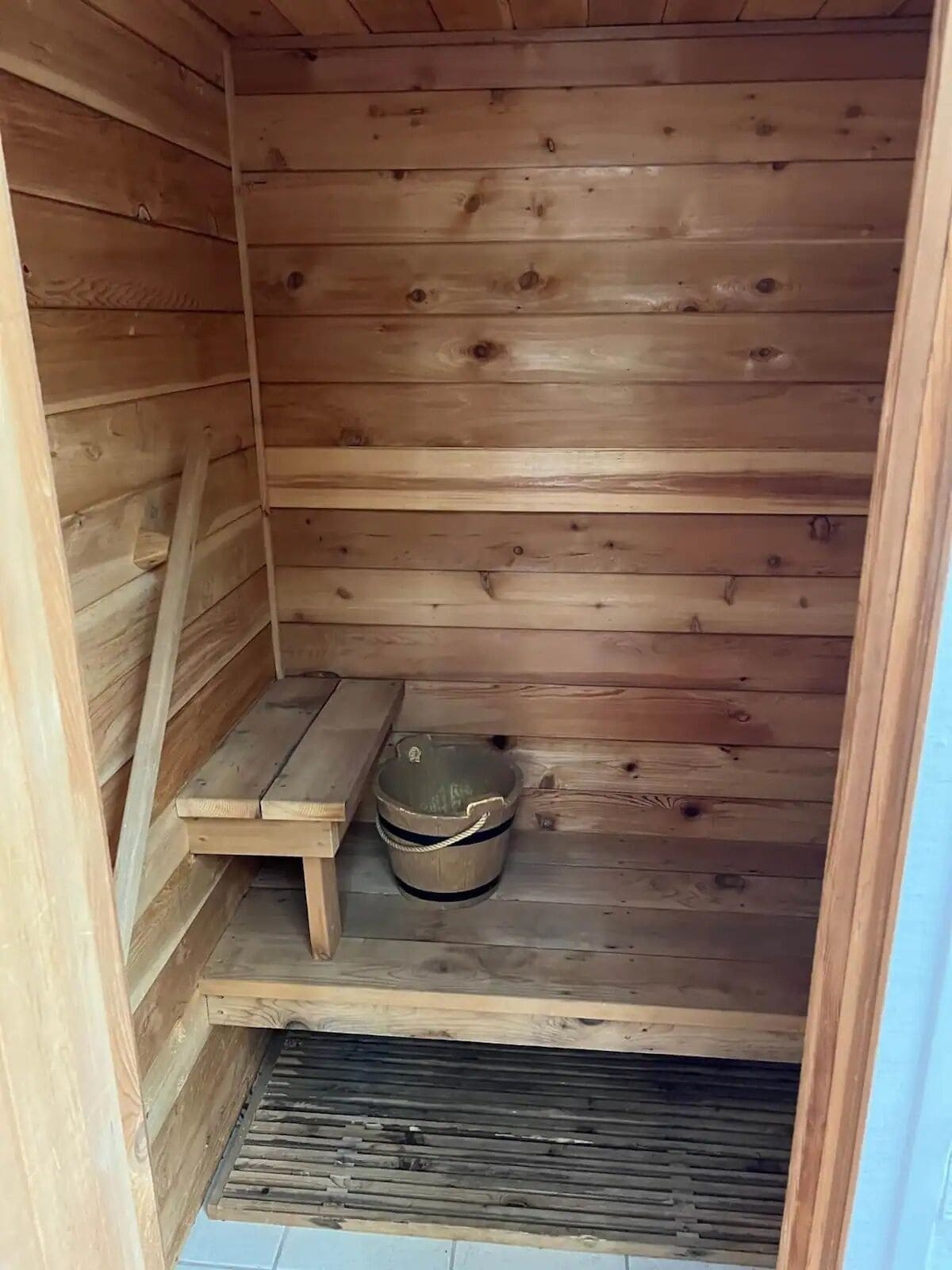 Un sauna en bois avec un banc et un seau.