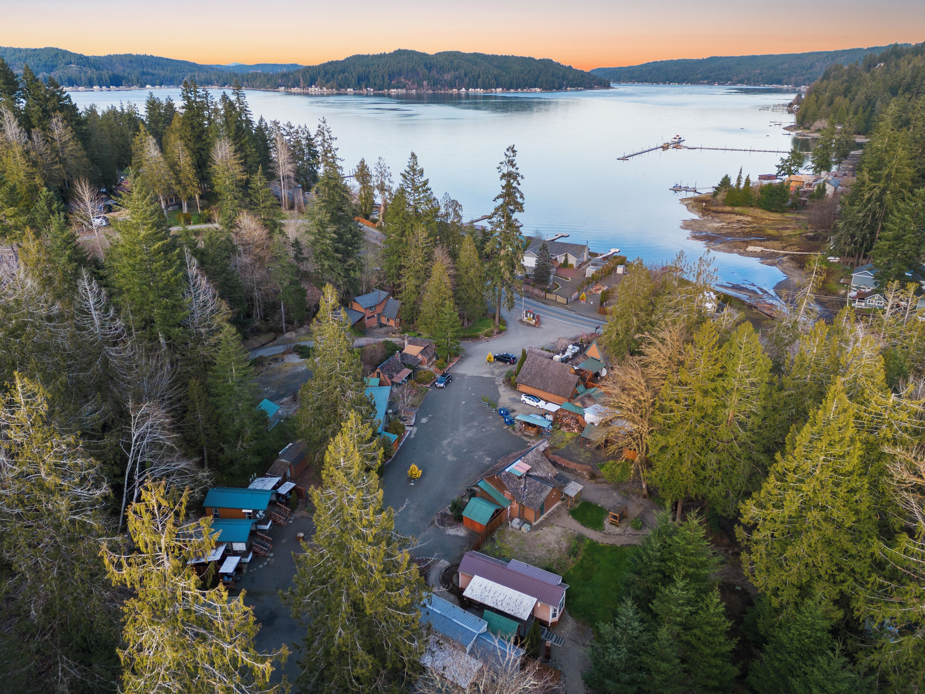 A lakeside cabin community with multiple houses, a dock, and a clear view of the lake.
