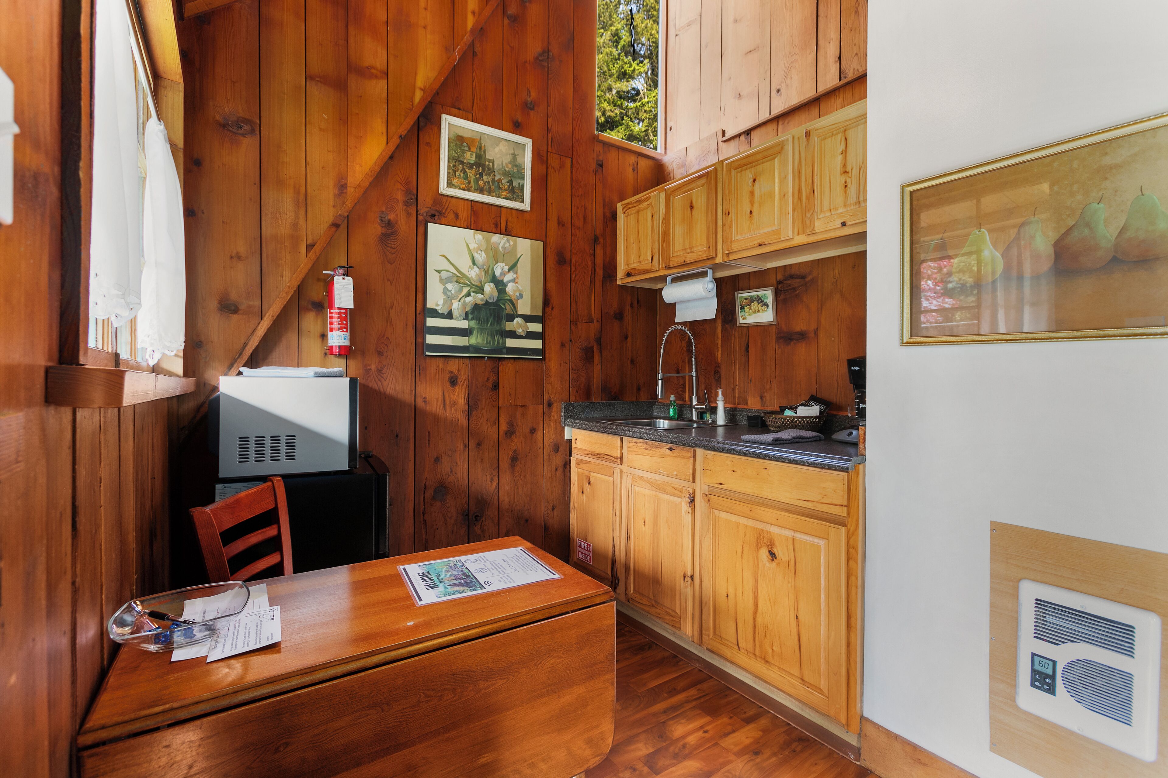 A wooden cabin with a kitchenette, a dining area, and a small television.