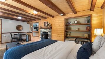 Una habitación acogedora con una cama, chimenea, escritorio y una estantería con diversos objetos.