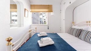 A hotel room with a bed, a window with a view, and a bedside table.