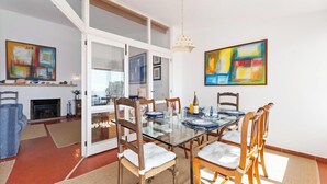 A dining area with a glass table, wooden chairs, and a fireplace.