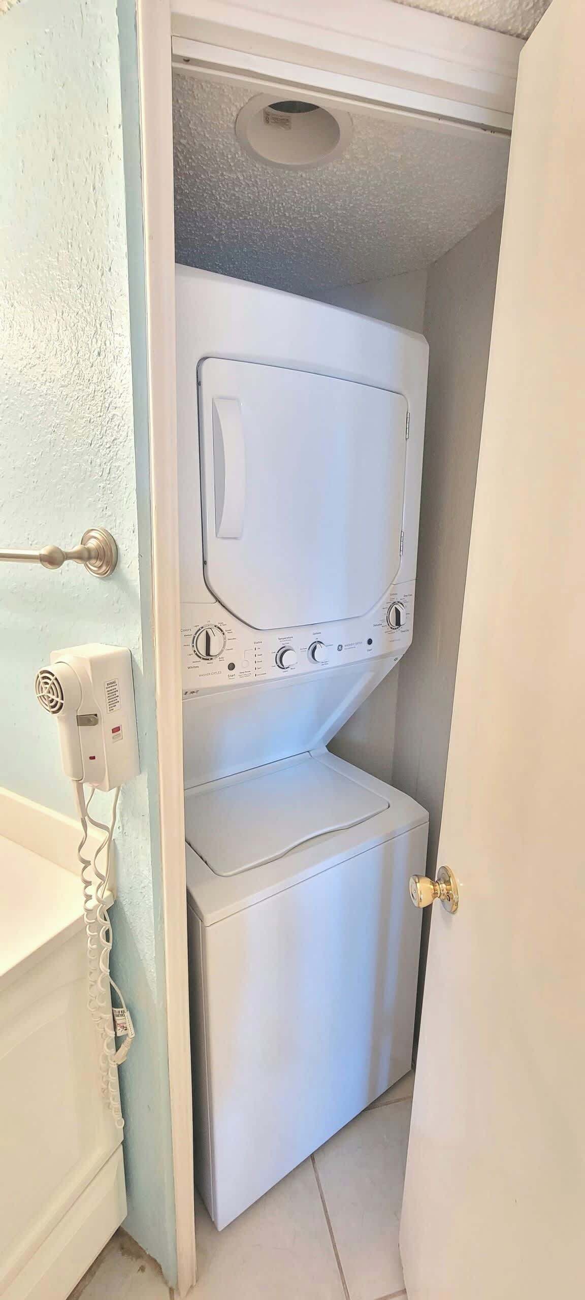 Una bugaderia petita amb una rentadora i una assecadora apilades, una presa d'electricitat i un timbre.