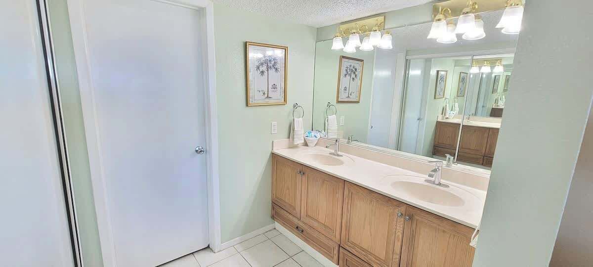A bathroom with a double sink vanity, a large mirror, and framed artwork on the wall.