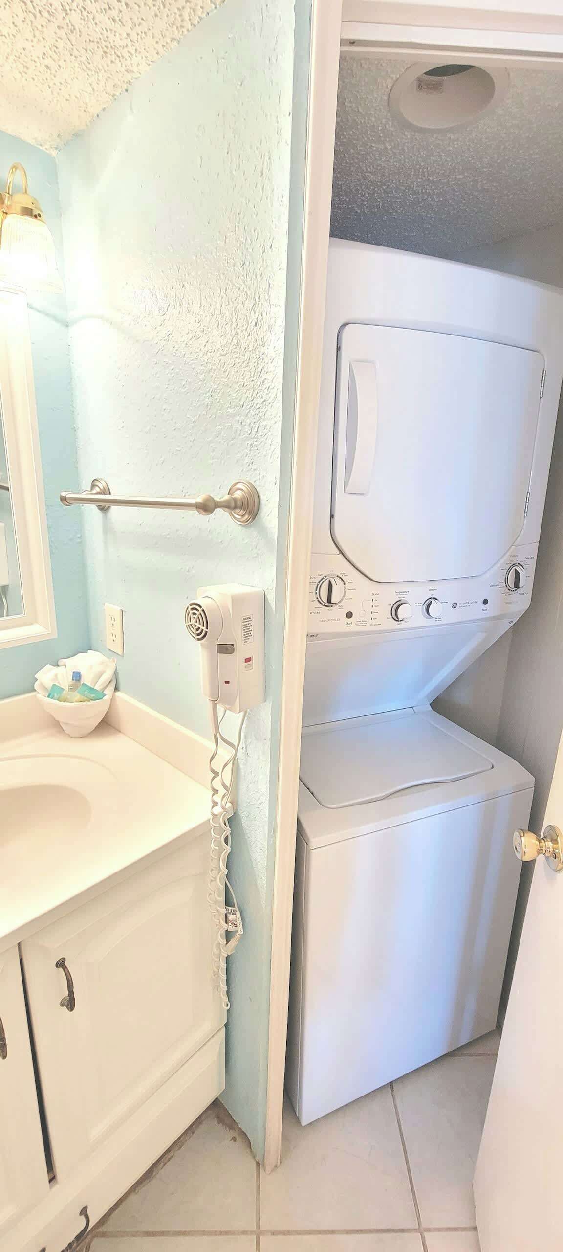 A compact bathroom with a sink, mirror, towel rack, and a wall-mounted dryer.