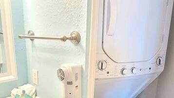 A compact bathroom with a sink, mirror, towel rack, and a wall-mounted dryer.