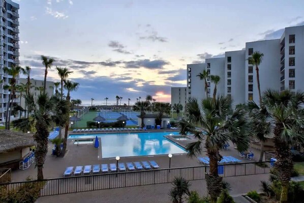 A hotel pool area with a large pool, sun loungers, and palm trees. - Direct Beach Very Large - Gas BBQ - Heated Pool (South Padre Island)