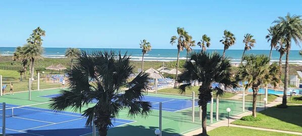 A tennis court with a view of the ocean and palm trees. - Direct Beach Very Large - Gas BBQ - Heated Pool (South Padre Island)