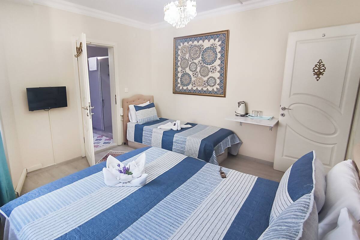 A hotel room with two beds, a television, a door, and a decorative wall piece.