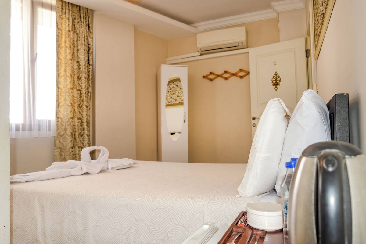 A hotel room with a bed, a wardrobe, a mirror, and a coffee maker.