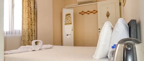 Una habitación de hotel con cama, armario, espejo y cafetera.