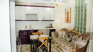 A modern kitchen with white cabinets, a dining table with chairs, and a decorative chandelier. - Ephesus Palace (Selçuk)