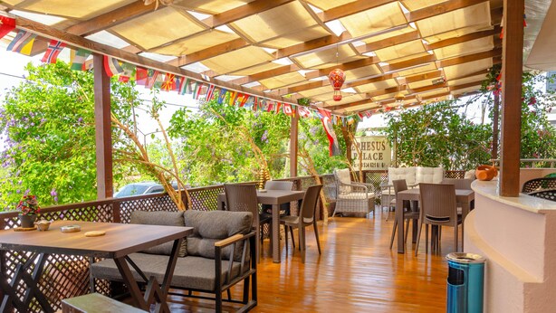 An outdoor patio area with wooden flooring, wicker furniture, and a covered seating area. - Ephesus Palace (Selçuk)