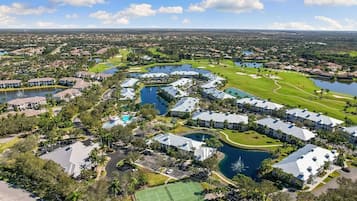 Un campo da golf con elementi d'acqua, un campo da tennis e edifici residenziali.