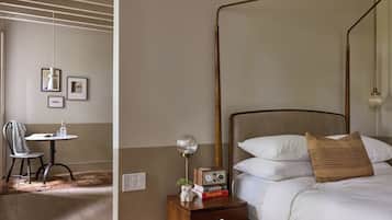 Una habitación de hotel con cama, mesita de noche, lámpara y una silla.