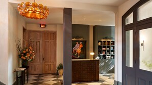 A lobby with a checkered floor, a reception desk, a chandelier, and a bookshelf. - Hotel Anna & Bel (Philadelphia)
