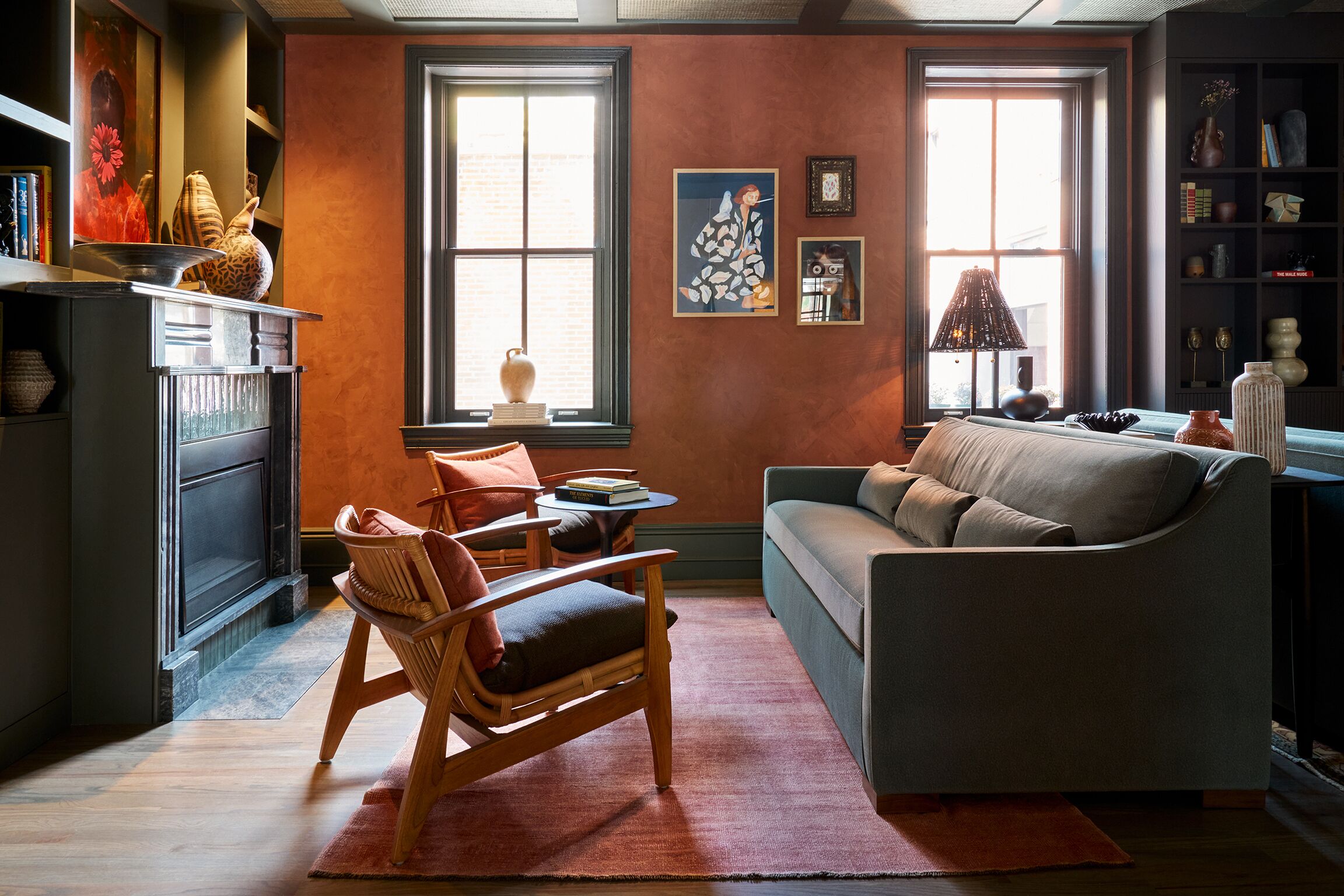 A cozy living room with a fireplace, a sofa, a wooden chair, and a bookshelf.