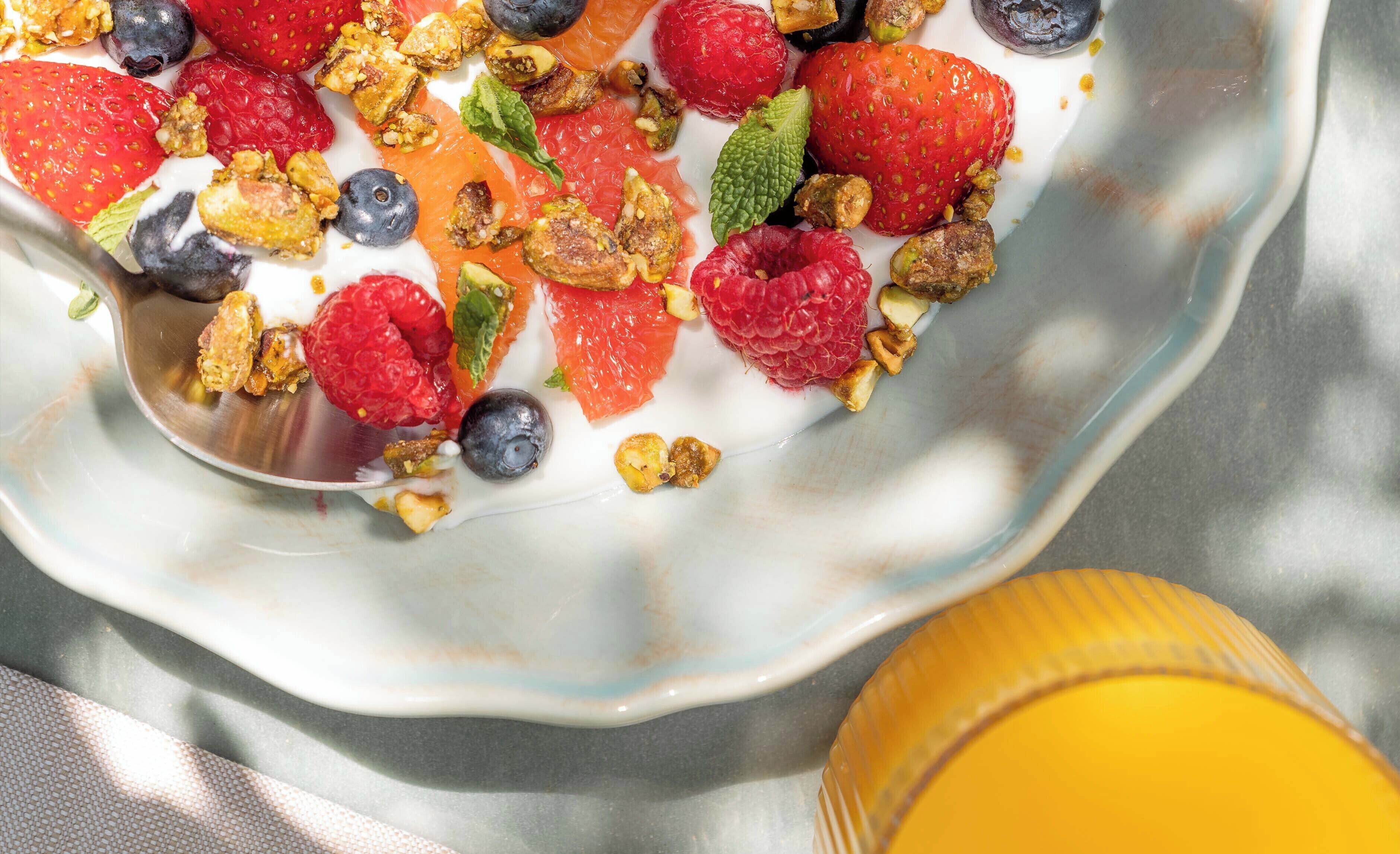 A bowl of yogurt topped with strawberries, blueberries, raspberries, and granola.