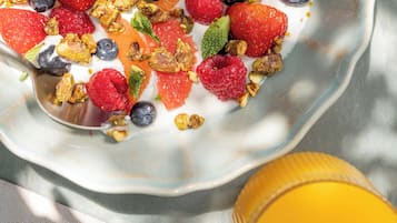 A bowl of yogurt topped with strawberries, blueberries, raspberries, and granola.