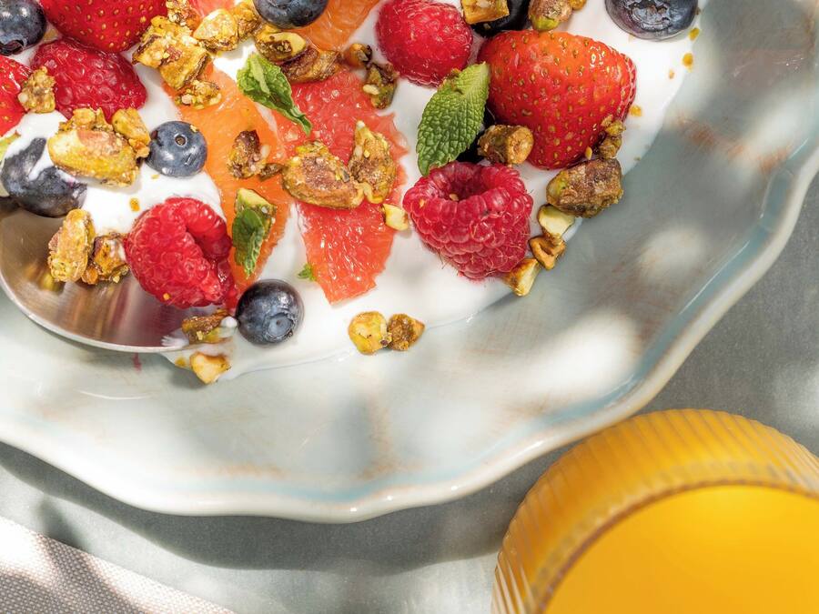 A bowl of yogurt topped with strawberries, blueberries, raspberries, and granola.