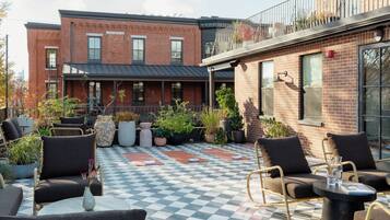 Une cour avec un sol à carreaux, des sièges en plein air et des plantes en pot.