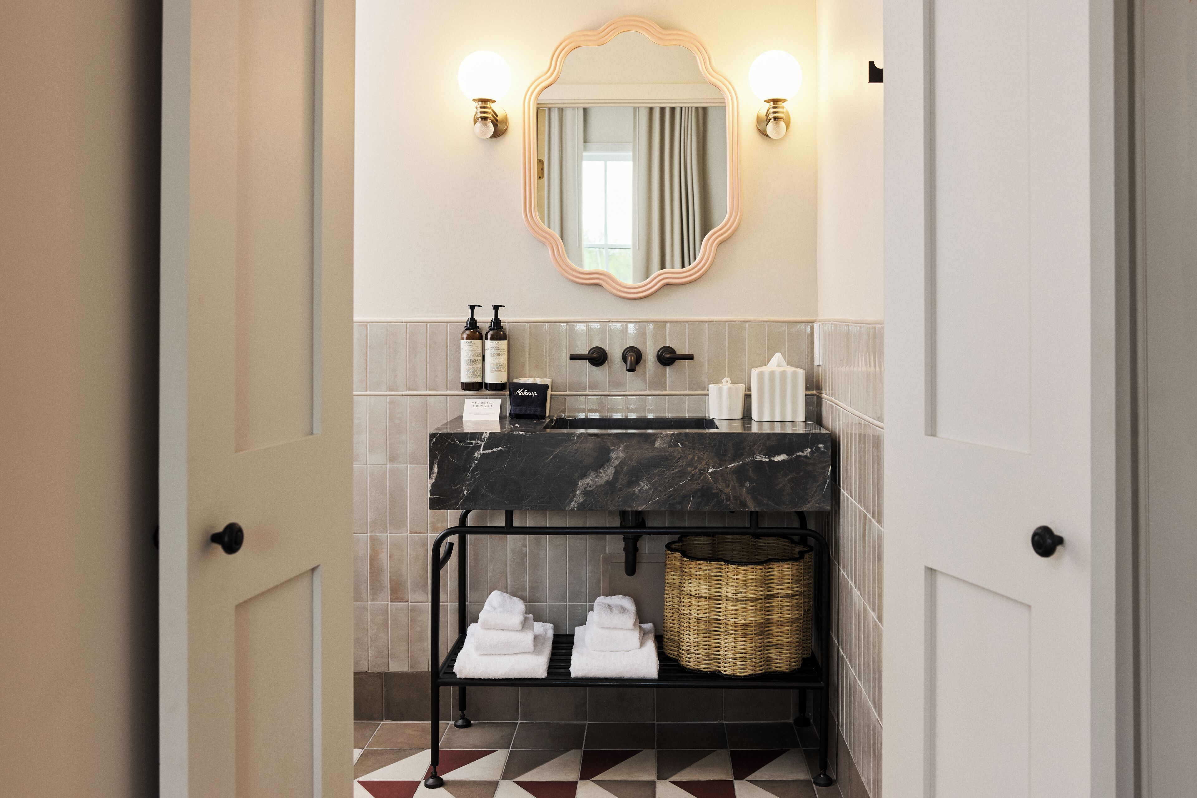 A modern bathroom with a marble sink, a large mirror, and a towel rack with folded towels.