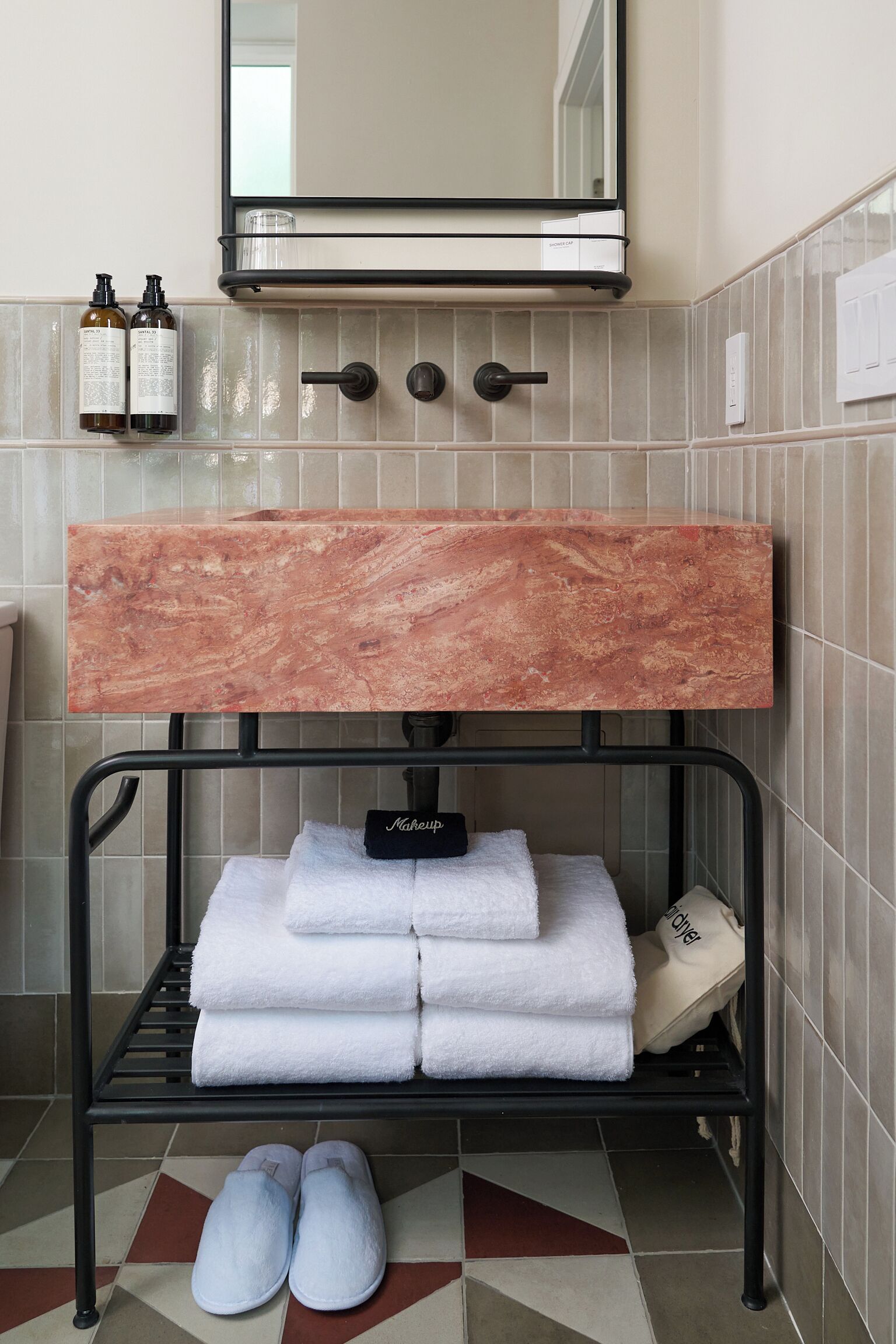 A bathroom with a marble sink, towel rack, and a mirror.
