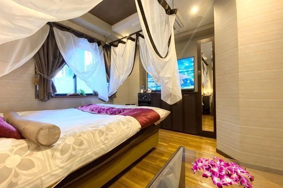 Een slaapkamer met hemelbed, houten vloer en uitzicht op de stad.