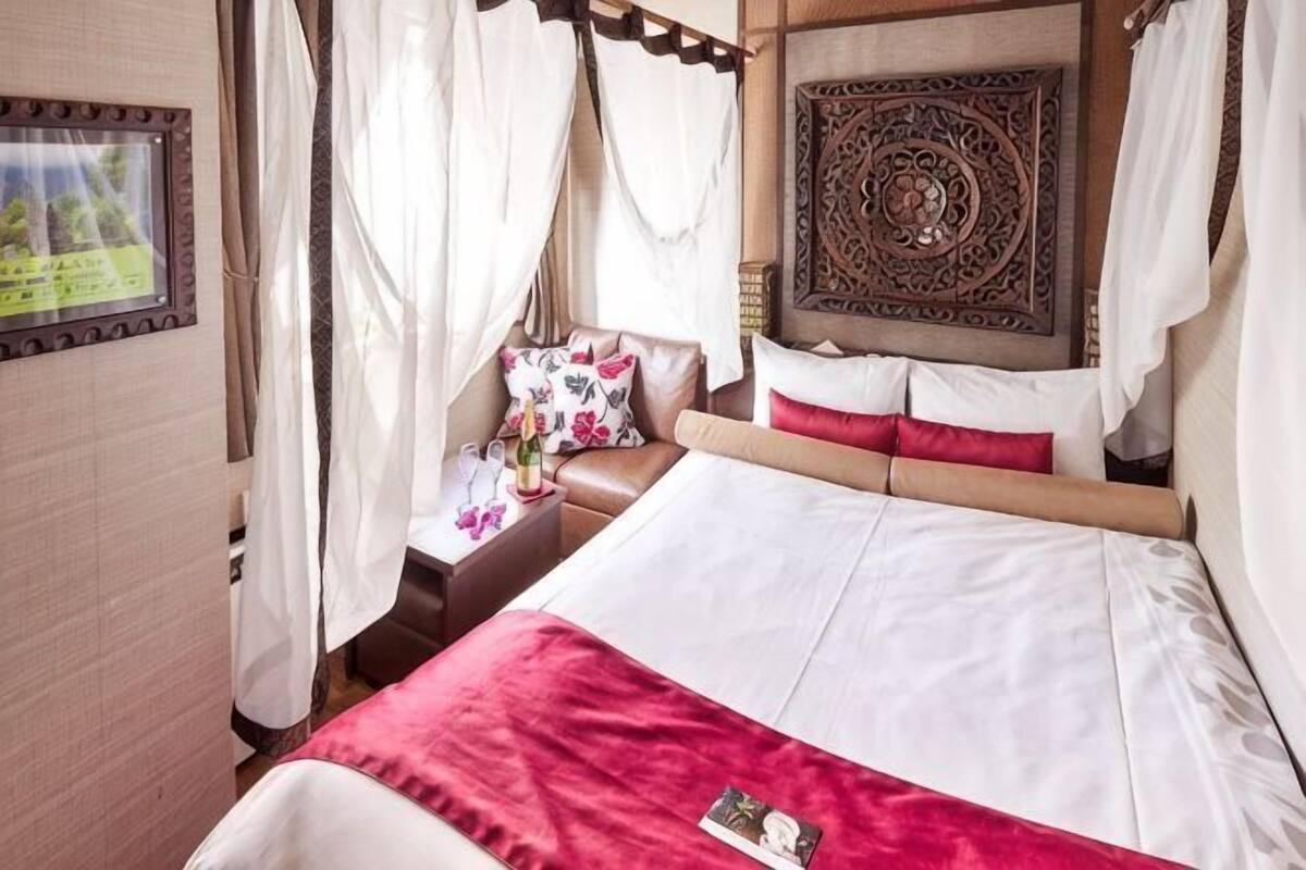 Een bed met hemelbed, een nachtkastje met lamp en een decoratief hoofdbord.