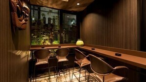 A bar area with a wooden counter, leather chairs, and a view of greenery outside. - Hotel Balian Resort Namba Shinsaibashi - Near Dotonbori (Osaka)