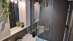Une salle de bain moderne avec une douche à parois de verre, un lavabo blanc et un miroir au-dessus.