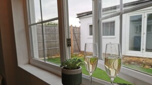 Deux verres de vin blanc sont posés sur un rebord de fenêtre, à côté d’une petite plante en pot.