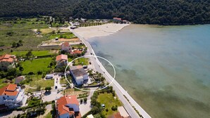 An aerial view of a coastal area with a beach, residential buildings, and a road leading to the shore. - Sea View Summer Paradise - Emily 1 (Kampor)