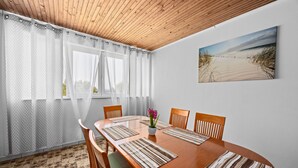 A dining area with a wooden table, chairs, and a painting of a beach scene. - Sea View Summer Paradise - Emily 2 (Kampor)
