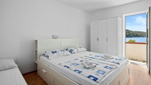 A bedroom with a bed, a wardrobe, and a view of a balcony with a scenic landscape. - Sea View Summer Paradise - Emily 2 (Kampor)