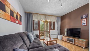 A modern living room with a large sectional sofa, a flat-screen TV, a wooden cabinet, and a large window with curtains. - Anamar- Three bedroom Apartment with Sea View (Supetarska Draga)