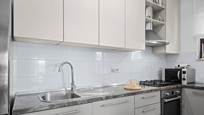 A modern kitchen with white cabinets, a stainless steel sink, a gas stove, and a built-in oven. - Anamar- Three bedroom Apartment with Sea View (Supetarska Draga)
