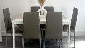 Una mesa de comedor con cuatro sillas, un jarrón con flores secas y una pared blanca.
