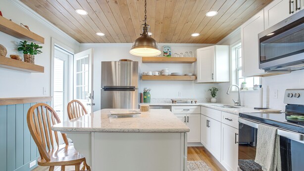 A modern kitchen with wooden ceiling, white cabinets, stainless steel appliances, and a central island with seating. - Unique Tangier Cottage w/ Chesapeake Bay Views! (Tangier)