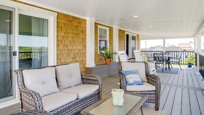 A covered outdoor area with wicker furniture, a glass table, and potted plants. - Unique Tangier Cottage w/ Chesapeake Bay Views! (Tangier)