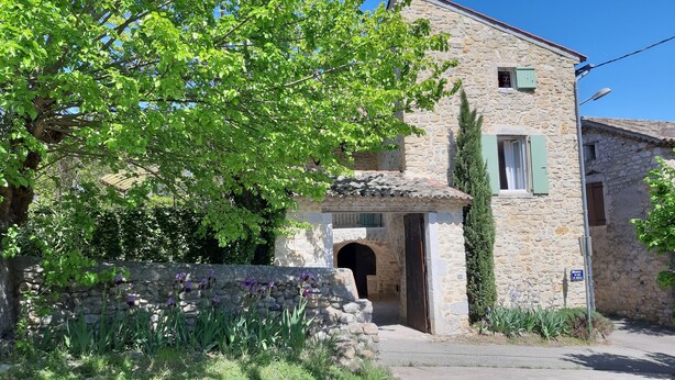 Un edificio de piedra con una entrada en arco tradicional, una ventana pequeña con contraventanas y un letrero que indica un restaurante.