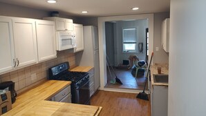 Una cocina con gabinetes blancos, encimera de madera, estufa y microondas.
