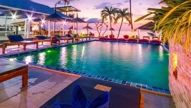 A pool area with lounge chairs, umbrellas, and a view of the ocean at sunset. - Bungalow - Sleeps 2 - Terrace - Beach Close (Koh Lan)