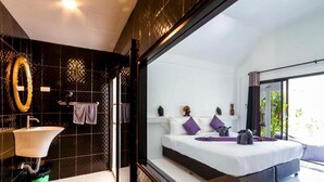 A modern bedroom with a large bed, a bathroom with a sink and mirror, and a view of greenery outside. - Bungalow - Sleeps 2 - Terrace - Beach Close (Koh Lan)