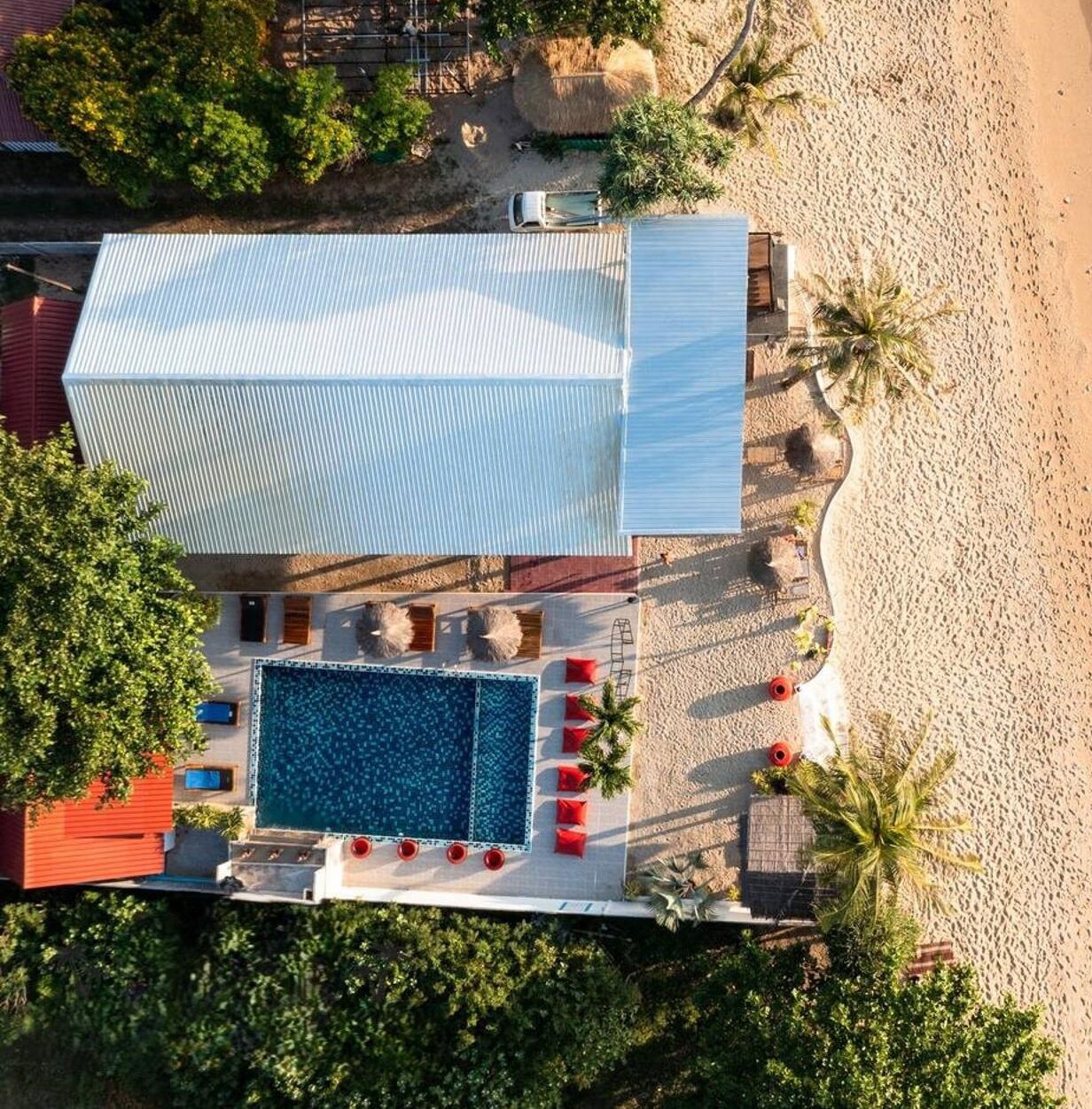 Un área de piscina en la azotea con una piscina grande, tumbonas y una zona de estar cubierta.