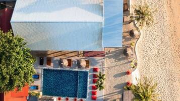 Un área de piscina en la azotea con una piscina grande, tumbonas y una zona de estar cubierta.