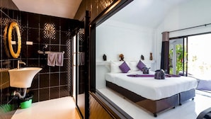 Un dormitorio moderno con una cama grande, un baño con lavamanos y espejo, y vistas al exterior.