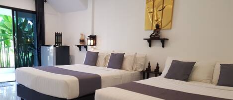 Habitación de hotel con dos camas, un ventanal con vistas a zonas verdes, una estatua de Buda montada en la pared y una obra de arte dorada decorativa.